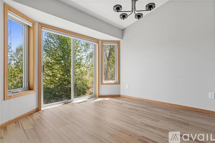A room with wooden floors and a large window with a view of trees.