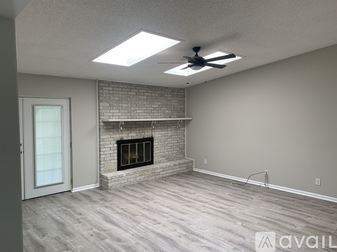 A spacious living room with a fireplace and a ceiling fan.