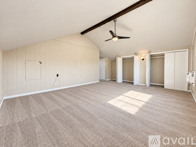 A spacious room with a carpeted floor and a ceiling fan.