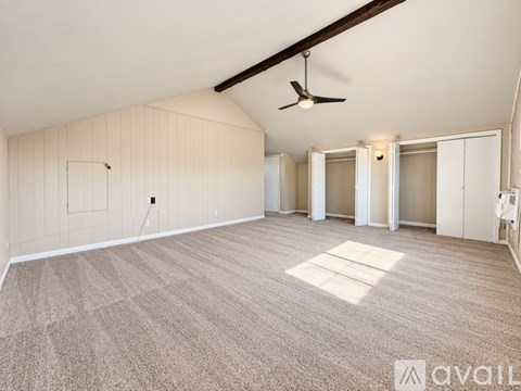 A spacious room with a carpeted floor and a ceiling fan.