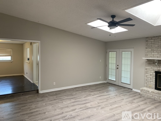 A spacious living room with a fireplace and a ceiling fan.