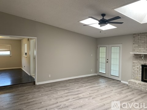 A spacious living room with a fireplace and a ceiling fan.
