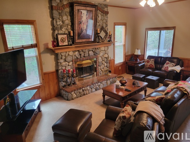 A living room with a stone fireplace and a large couch.