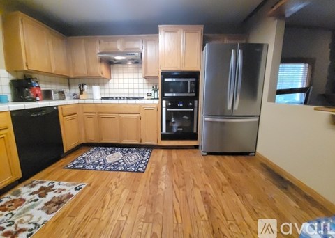 A kitchen with wooden cabinets and a black fridge.