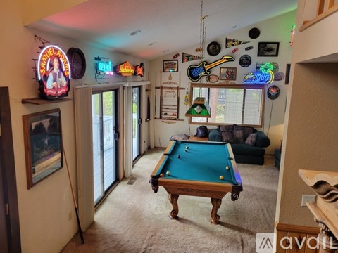 A pool table in a room with a neon sign that says "Smokey and the Bandit".