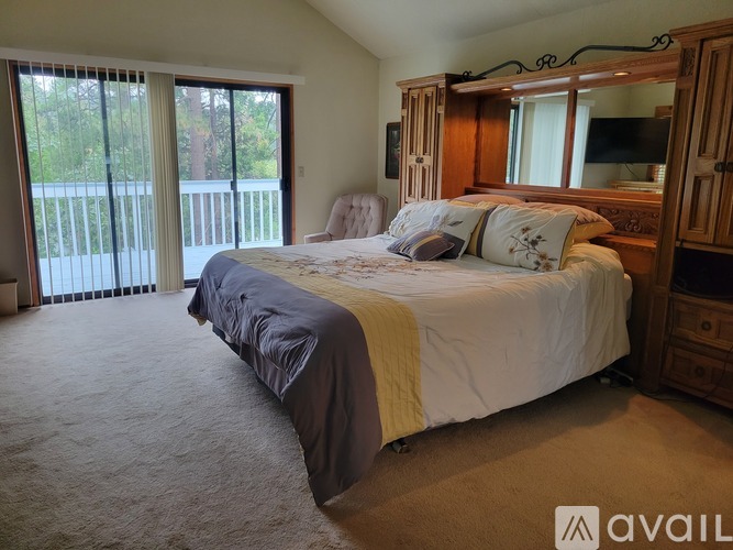 A bedroom with a large bed and a balcony with sliding doors.