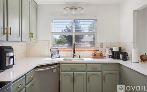 A kitchen with green cabinets and a white countertop.
