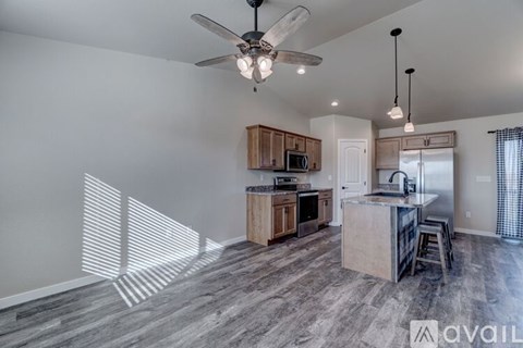 A modern kitchen with wooden cabinets and a ceiling fan.
