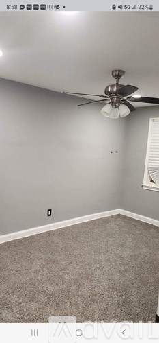 A room with a ceiling fan and carpeted floor.