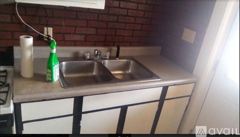 A kitchen sink with a green bottle on the counter.