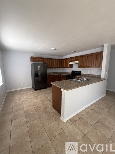 A kitchen with a black fridge and brown cabinets.