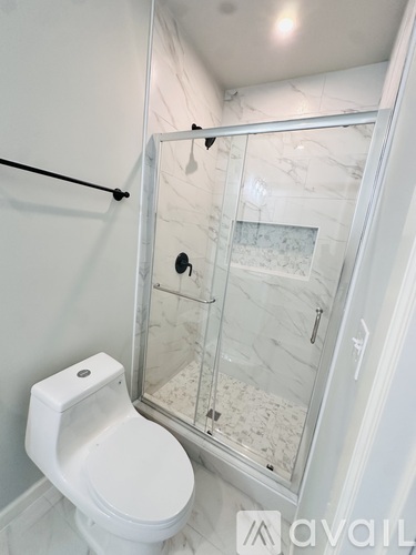 A white toilet with a glass shower stall in the background.