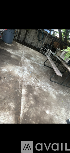 A concrete floor with a bench and a trash can.