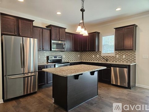 A kitchen with dark wood cabinets and a stainless steel refrigerator.