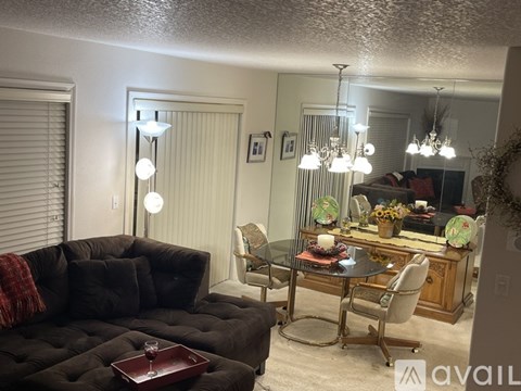 A living room with a black couch and a glass table with chairs.