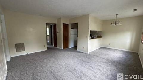 A spacious living room with a grey carpet and a white ceiling.