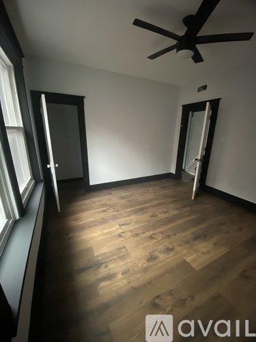A room with a ceiling fan and wooden flooring.