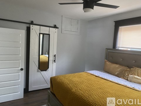 A bedroom with a bed, a ceiling fan, and a sliding door.