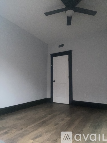 A room with a ceiling fan and a door.