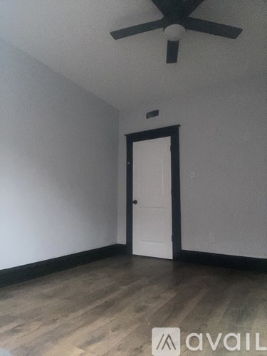 A room with a ceiling fan and a door.