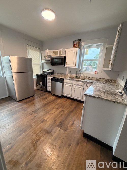 A kitchen with a refrigerator, microwave, oven, and sink.
