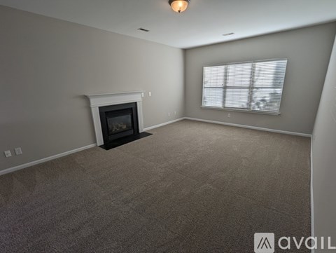 A living room with a fireplace and carpeted floor.