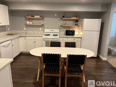 A kitchen with a white table and chairs in the middle of it.