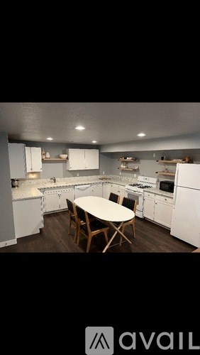 A kitchen with white appliances and a table in the middle.