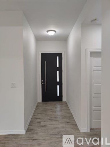 A hallway with a black door and wooden flooring.
