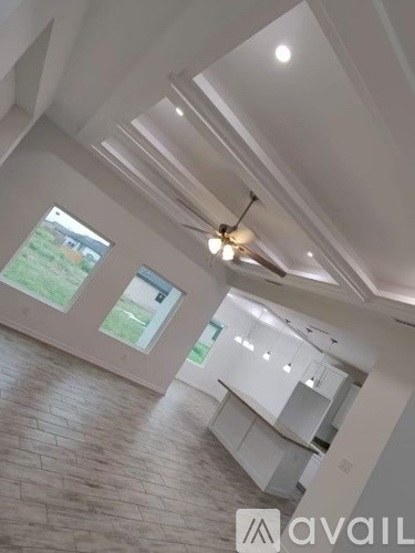A modern kitchen with a large island and pendant lights.