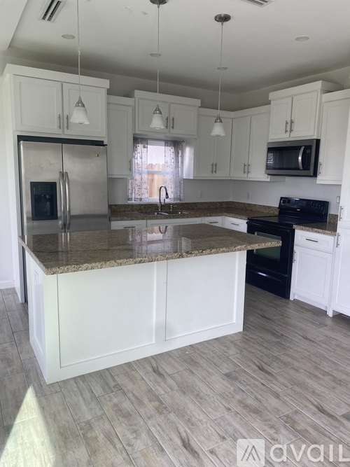 A kitchen with granite countertops and white cabinets.