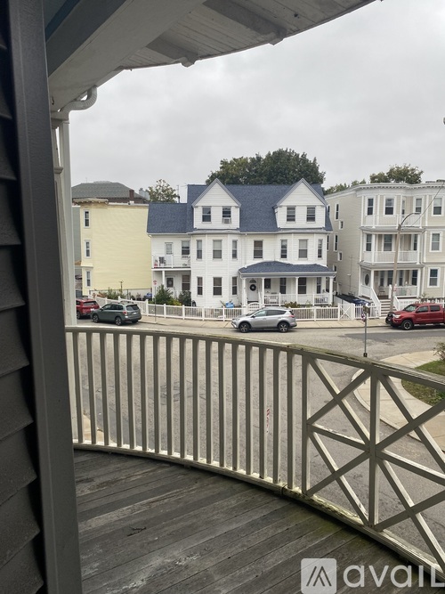 A view from a porch looking at a street with cars and buildings.