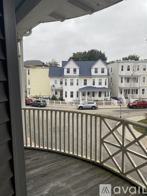 A view from a porch looking at a street with cars and buildings.