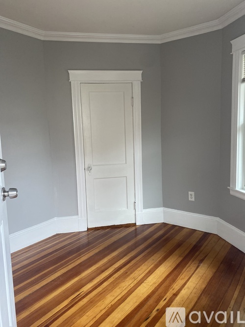 A room with a white door and wooden flooring.