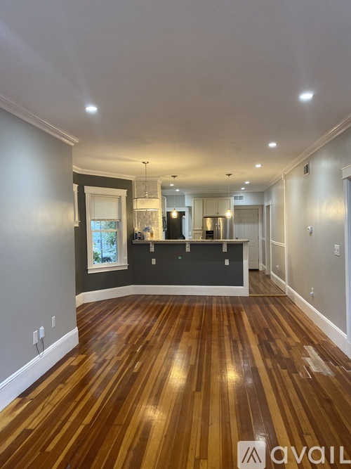 A spacious room with wooden flooring and a large mirror on the wall.