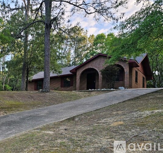 A house with a driveway in front of it surrounded by trees.