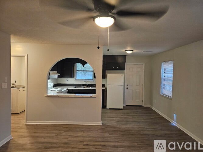 A room with a ceiling fan and a window overlooking a kitchen.