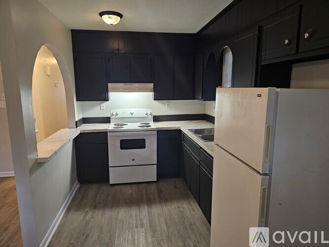 A kitchen with black cabinets and a white refrigerator.