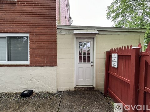 A red fence with a sign on it is in front of a house.