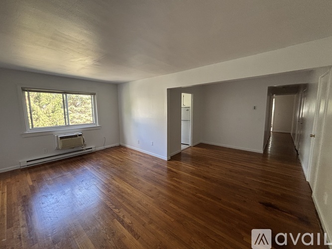 A spacious room with wooden floors and a window.