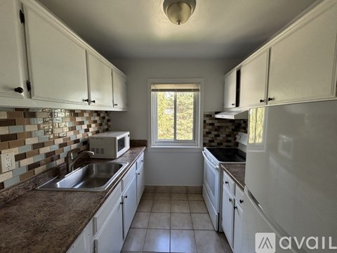 A kitchen with white cabinets and a checkered backsplash.