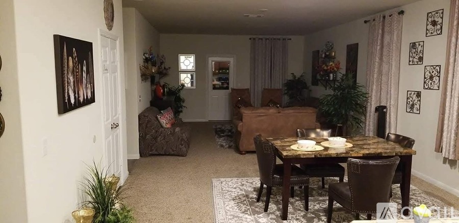 A dining room with a table set for two and a couch.