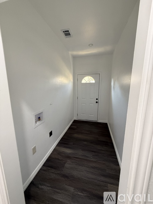 A hallway with a white door and grey flooring.