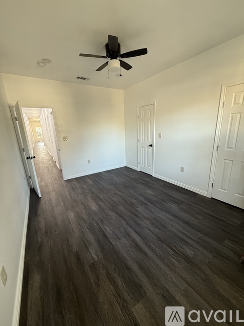 A room with a ceiling fan and wood flooring.