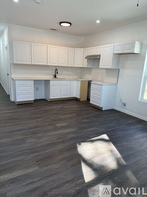 A kitchen with white cabinets and a wooden floor.
