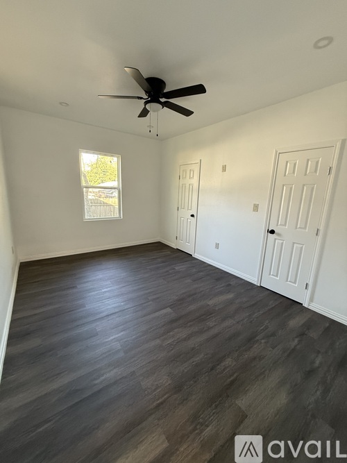 A room with a ceiling fan and wood flooring.