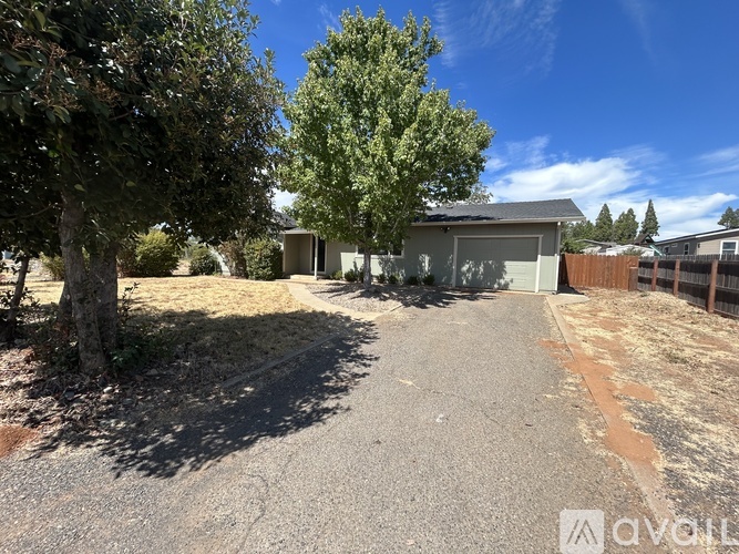 A gravel driveway leads to a garage with a tree on the left.