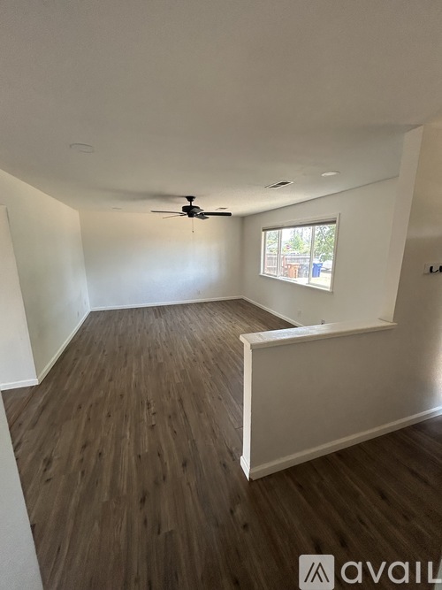 A room with a ceiling fan and wooden flooring.