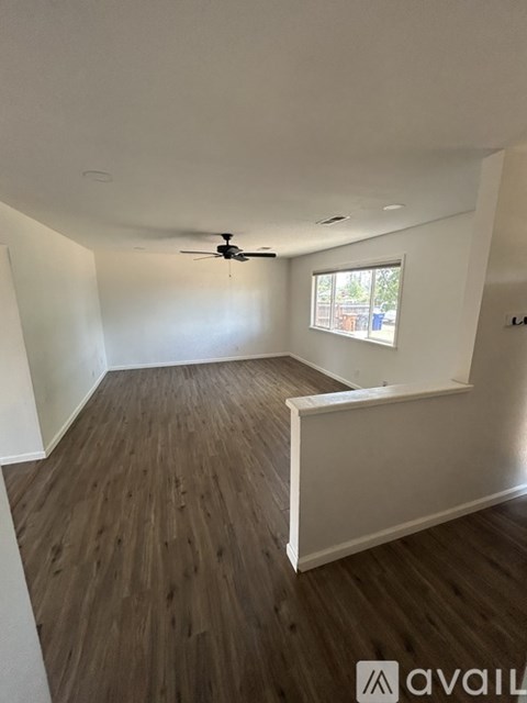 A room with a ceiling fan and wooden flooring.