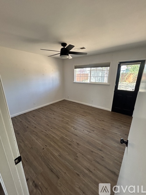 A room with a ceiling fan and wooden flooring.